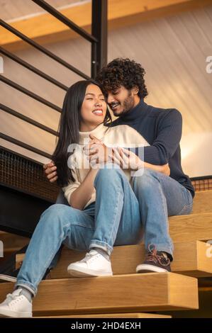 Uomo che abbraccia una donna seduta sulle scale Foto Stock