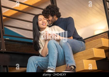 Uomo che abbraccia sussurrando in orecchio di donna Foto Stock