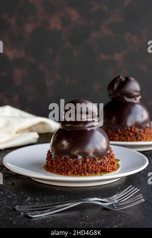 Profiteroles torta su uno sfondo scuro. Torta con cioccolato liquido e profiteroles. Primo piano. Vista verticale Foto Stock