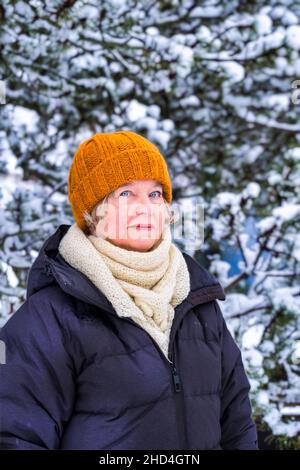 Donna di mezza età all'aperto in inverno con pino innevato Foto Stock