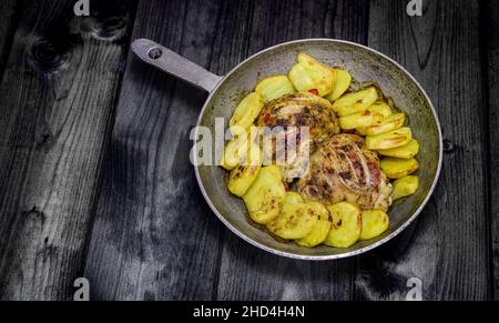 Foto d'epoca - vecchia padella con pollo e patate al forno. Menu brutale. Spazio di copia. Foto Stock
