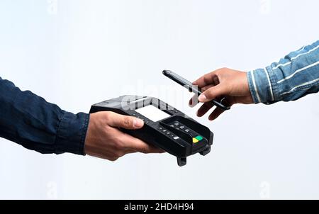 Mani che tengono il dispositivo POS e lo smartphone su uno sfondo bianco isolato. Concetto di pagamento semplice e senza contatto. Foto Stock