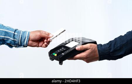 Mani che tengono il dispositivo POS e la carta di credito su sfondo bianco isolato. Concetto di pagamento semplice e senza contatto. Foto Stock