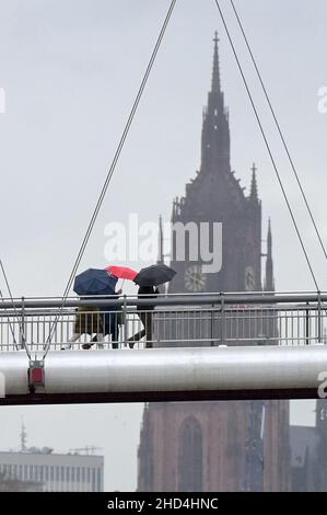 03 gennaio 2022, Hessen, Francoforte sul meno: Tre passeggini costeggiano l'Holbeinsteg con ombrelloni. La cattedrale imperiale di San Bartolomeo è visibile sullo sfondo. Foto: Niels Babbel/dpa Foto Stock