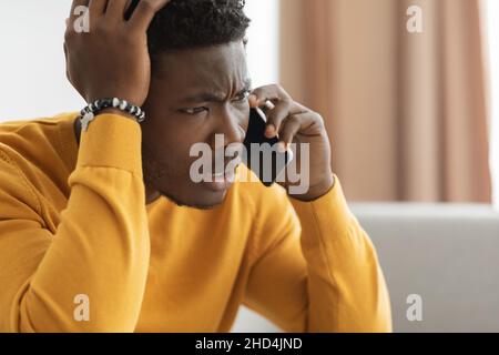 Un ragazzo afroamericano perplesso che ha avuto una conversazione telefonica Foto Stock