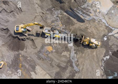 Vista dall'alto del nastro trasportatore del frantumatore di pietre escavatori pesanti che caricano pietre nel frantumatore Foto Stock