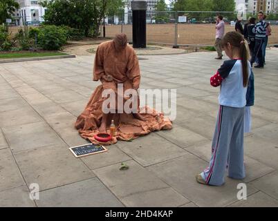 Giovane ragazza in piedi di fronte ad un enternainer Street vestito come l'Alchemista. Londra, Regno Unito. Foto Stock