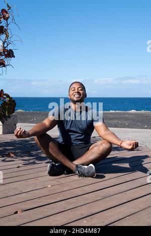 L'uomo felice meditating in posizione di loto mentre fa yoga sulla spiaggia Foto Stock