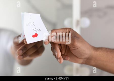 Maschio mano mettere Sticky Note con i Love You testo sullo specchio Foto Stock