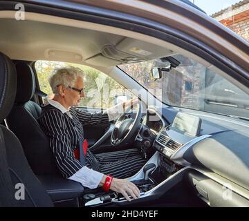 Donna anziana alla guida di un'auto costosa Foto Stock