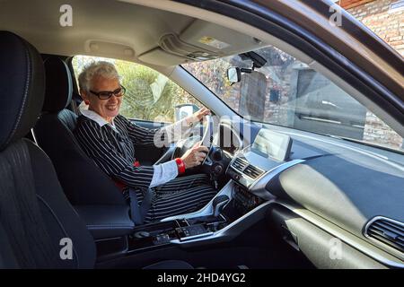 Donna anziana alla guida di un'auto costosa Foto Stock