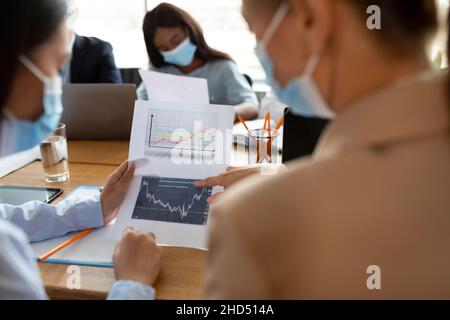 Uomini d'affari che indossano maschere protettive per il viso che lavorano con documenti in ufficio Foto Stock