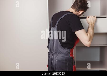 Assemblatore di mobili installazione cassetti in armadio. Foto Stock