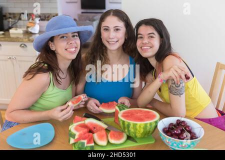 Tre amici del college femminile posano per una foto con la frutta estiva Foto Stock