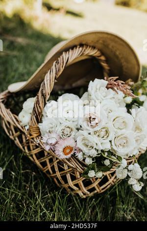 Primo piano di fiori freschi in un cesto tessuto con grande cappello da sole Foto Stock