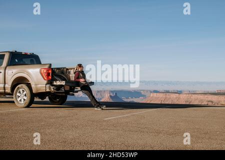 La donna si appoggia contro il portellone del pick-up guardando la vista, Utah Foto Stock