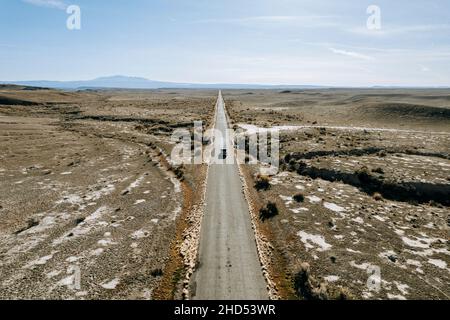 immagine aerea camion solitario che guida su una lunga strada rettilinea attraverso il deserto Foto Stock