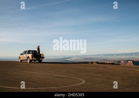 La donna si alza sul letto del camion di presa guardando la vista, Moab, Utah. Foto Stock