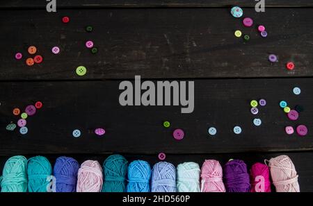 palline di lana colorate su pavimento di legno marrone con bottoni colorati Foto Stock