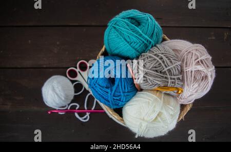 palline di lana colorate su terreno di legno marrone scuro per artigianato fatto a mano Foto Stock