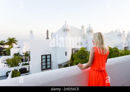 Giovane ragazza in piedi sul balcone che si affaccia sul mare Foto Stock