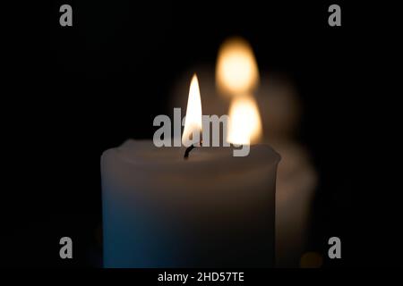 Tre candele che bruciano isolate su sfondo nero. Foto di alta qualità. Foto Stock