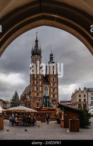 Cracovia, Polonia-Dicembre 17,2021. Basilica di Santa Maria e famoso mercato di Natale sulla piazza principale, Rynek Glowny, capanne in legno decorate con chee affumicate Foto Stock