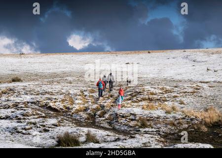 Una famiglia che cammina attraverso la neve sul selvaggio Rough Tor a Bodmin Moor in Cornovaglia. Foto Stock