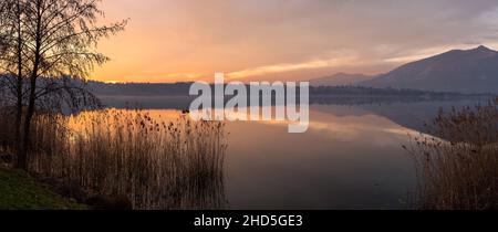 Tramonto sul lago con bellissimi riflessi di cielo e paesaggio, Como, Lombardia, Italia Foto Stock