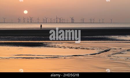 La luce del sole colorata si riflette sulla limo sulla spiaggia di Crosby. Foto Stock