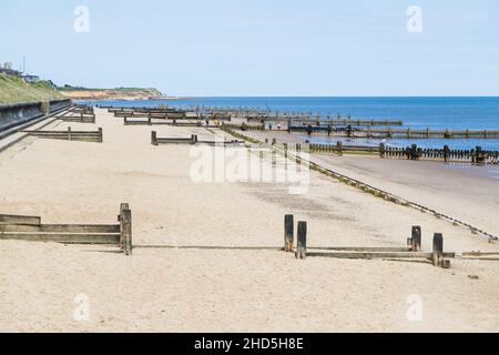 Groynes legno linea la spiaggia a Cart Gap sulla costa nord del Norfolk. Foto Stock