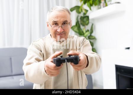 Uomo anziano che gioca il videogioco su sfondo bianco Foto Stock