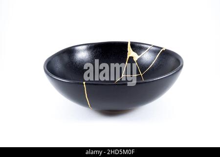 Kintsugi oro crepe restauro, giapponese nero ciotola fissato con l'antica tecnica di restauro kintsukuroi, la bellezza delle imperfezioni, rappresentano Foto Stock