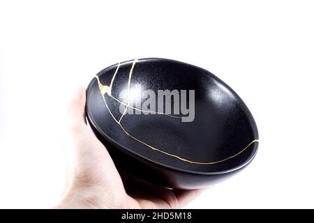 Kintsugi oro crepe restauro, giapponese nero ciotola fissato con l'antica tecnica di restauro kintsukuroi, la bellezza delle imperfezioni, rappresentano Foto Stock