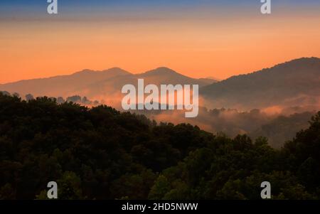 Il sole si adagia sulle Smoky Mountains nel North Carolina e la nebbia che si assestano nella valle Foto Stock