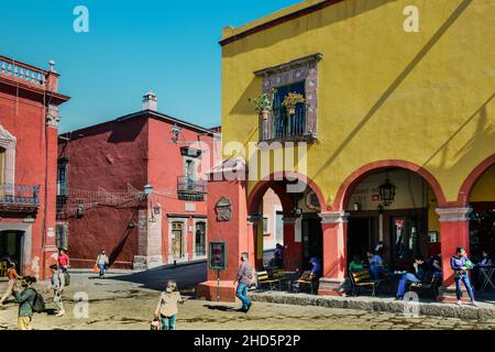 Vecchi edifici coloniali spagnoli e la gente che si fresano sulla piazza El Jardin godendo di vita caffè e shopping a El Centro a San Miguel de Allende, MX Foto Stock