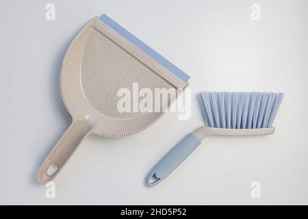 Set di sessola per il cestino dei rifiuti. Paletta in plastica grigia e blu e spazzola a mano su sfondo bianco. Pulizia della casa, chores concetto domestico. Vista dall'alto, spazio di copia Foto Stock