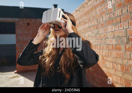 Donna che guarda attraverso gli occhiali di protezione per la realtà virtuale sul cantiere Foto Stock
