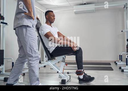 Paziente maschile che si allena utilizzando l'attrezzatura fitness Foto Stock