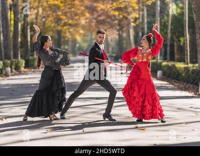 Uomo con due ballerine di flamenco che ballano in un parco Foto Stock