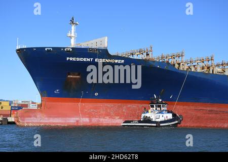 Tugs docking nave container APL Presidente Eisenhower, Porto di Oakland. Trasporto commerciale e navi container a San Francisco Bay, California Foto Stock