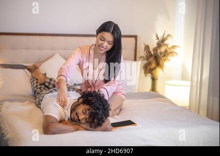 Donna che tocca con le mani la schiena dell'uomo menzogna Foto Stock