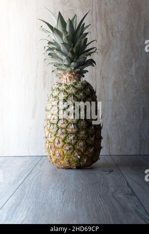 ananas e arance in primo piano su legno su sfondo marmoreo. Hald in ombra Foto Stock