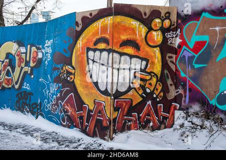 Street art. Graffiti murali arancioni ridenti sulla recinzione del cantiere nel quartiere Suvilahti di Helsinki, Finlandia. Foto Stock