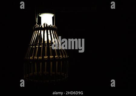 Una lampada con paralumi di una gabbia in bambù in luci basse. Punti di messa a fuoco selettivi Foto Stock