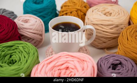 Primo piano di matasse di cotone multicolore e una tazza di caffè nero Foto Stock