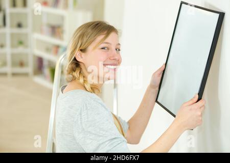 donna appesa un'immagine bianca sulla parete Foto Stock