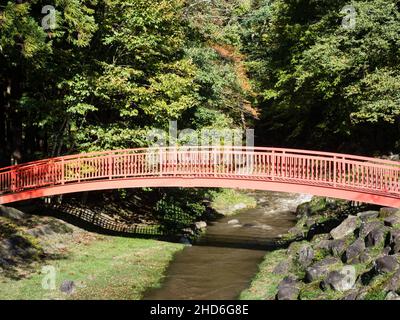 Ponte rosso sul fiume Togawa che conduce al Buddha di pietra di Manji a Shimosuwa - Prefettura di Nagano, Giappone Foto Stock