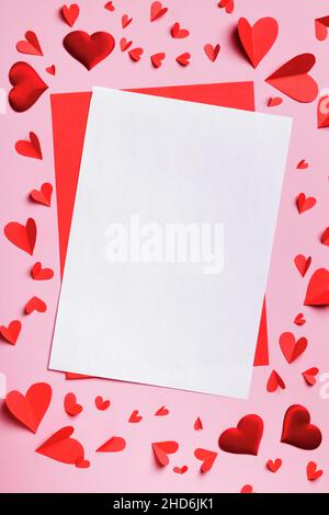 Concetto di giorno di San Valentino lettera d'amore. Un foglio bianco bianco bianco e un cuore di carta su sfondo rosa. Foto Stock
