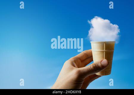 nube gelato. mano con cialda tazza contro cielo blu. spazio copia Foto Stock